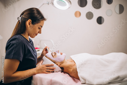 Cosmetologist applying mask on a face of client in a beauty salon photo