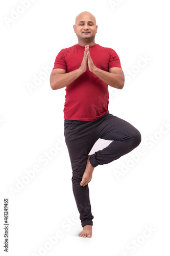 Portrait of a bald man standing and doing yoga against plain white background.