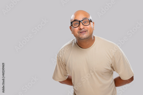 Portrait of a bald man wearing eyeglasses smiling against plain background.