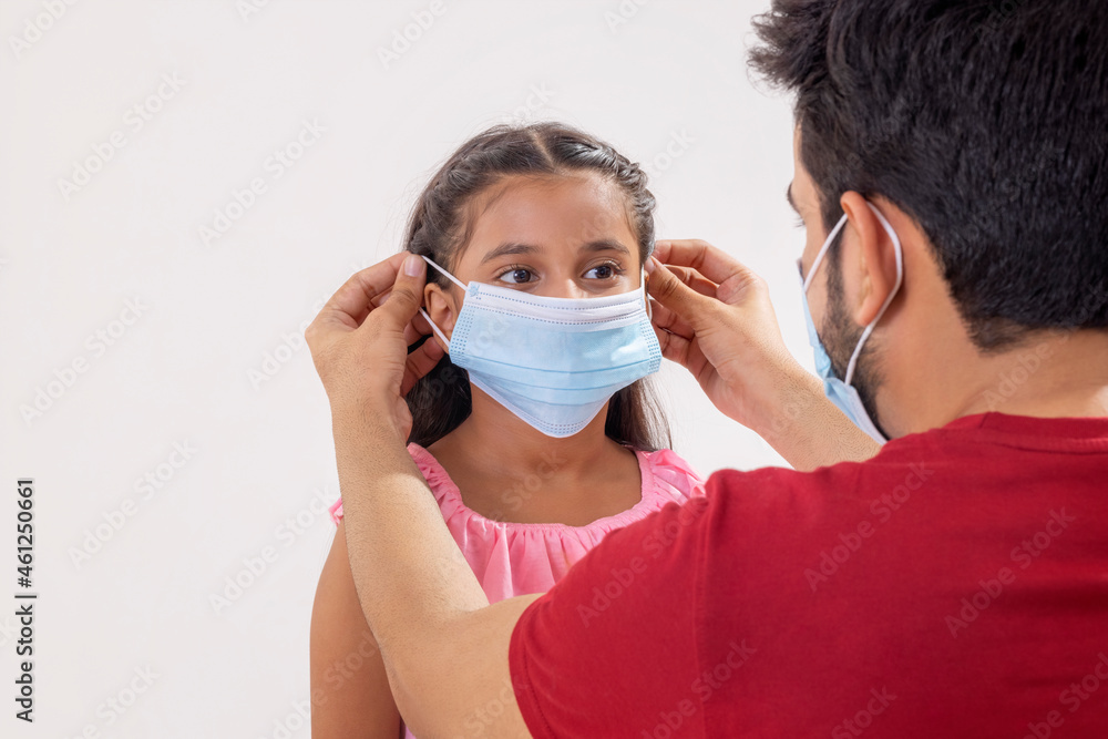 A FATHER PROTECTING DAUGHTER FROM PANDEMIC BY PUTTING FACE MASK 