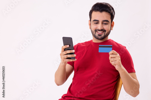 A MAN SITTING AND DOING ONLINE TRANSACTION ON MOBILE PHONE