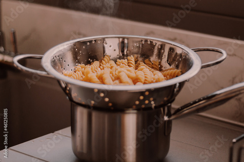 Hot freshly cooked pasta. Boiled makaroni at modern high-tech kitchen with gray kitchen sink