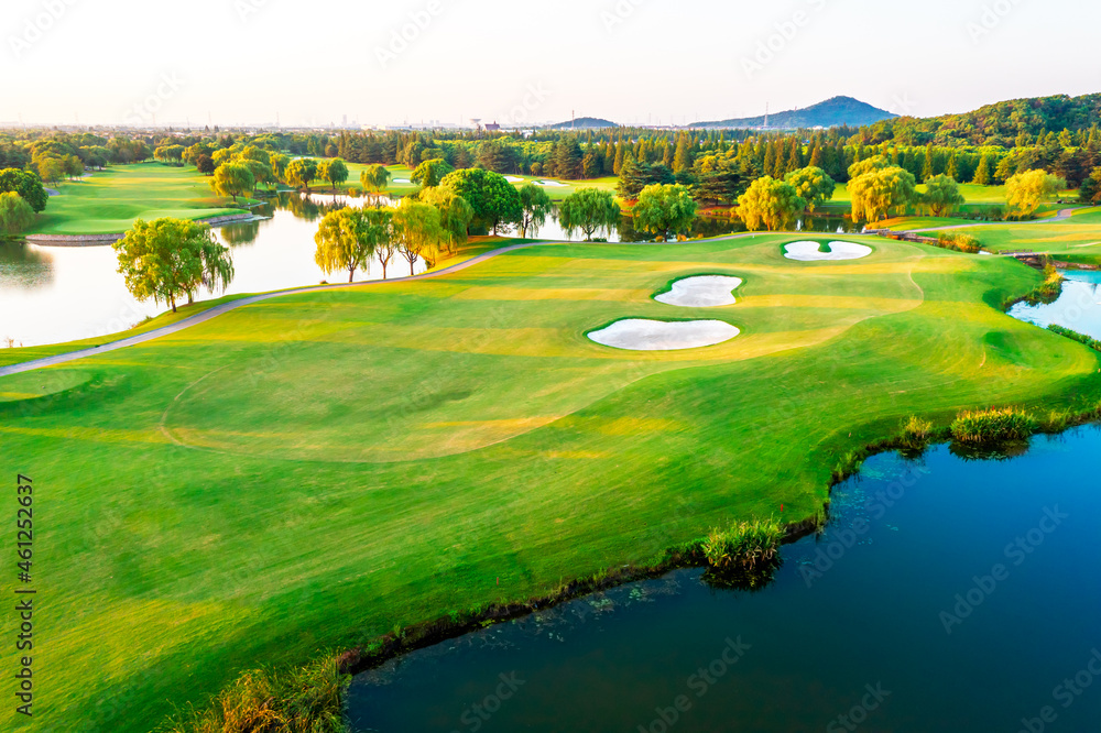 Aerial view of green lawn and forest on golf course.Green golf course scenery at sunset.