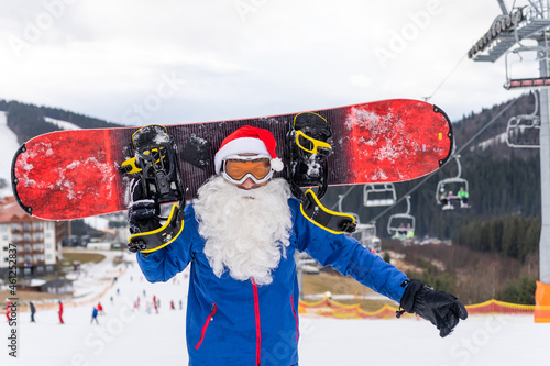 a man in a santa hat with a snowboard at a ski resort photo