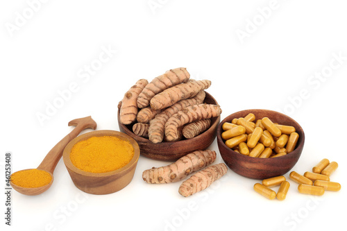 Turmeric root spice with powder and dietary supplement capsules. Food seasoning and natural herbal medicine. Is anti inflammatory, an antioxidant with many health benefits. On white.