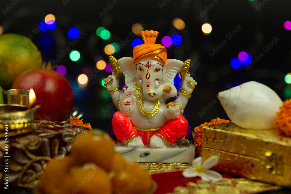 Moorti Murati of Ganpati Bappa Morya In Orange Pagdi For Worship On Diwali Puja New Year Deepawali Ganesh Chaturthi Or Shubh Deepavali Pooja. Laddu Sweet Ladoo And Shankh in Blur With Bokeh