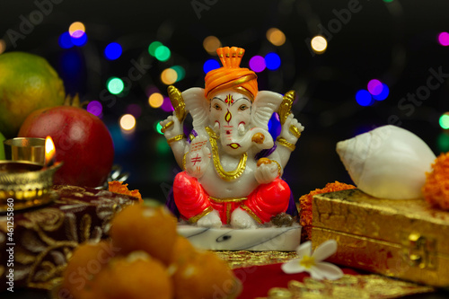 Moorti Murati of Ganpati Bappa Morya In Orange Pagdi For Worship On Diwali Puja New Year Deepawali Ganesh Chaturthi Or Shubh Deepavali Pooja. Laddu Sweet Ladoo And Shankh in Blur With Bokeh