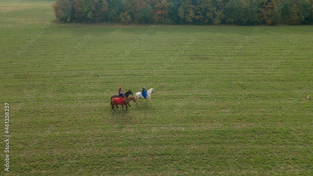 Aerial view of group of fox hunters on the horses in the autumn field. Equestrian riding sport in a countryside. Aerial view of group of fox hunters on the horses in the autumn field. Equestrian riding sport in a countryside.