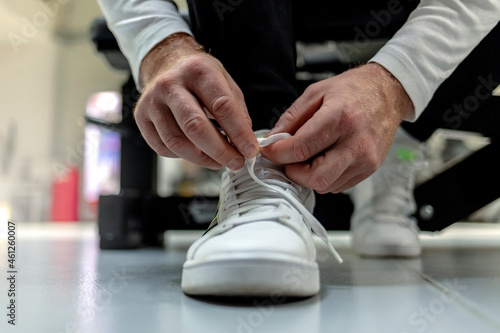Cropped shot of an unrecognizable sportsman tying his shoelaces in a gym. Shot of an unrecognizable man tying his shoelaces in the middle of his exercise routine. Close up.