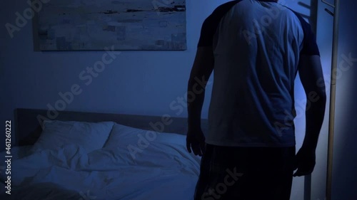slow motion of sleepy man in pajamas going to bed at night