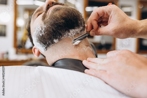Man getting haircut at the barbershop. Professional barber at work process. Beauty, selfcare, style, fashion, healthcare and male cosmetics concept.