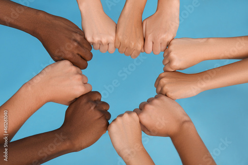 Billede på lærred Group of multiracial people joining fists together on light blue background, clo