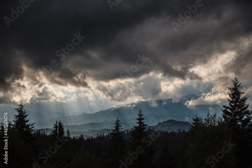 Dark heavy clouds with sunbeams over majestic mountains