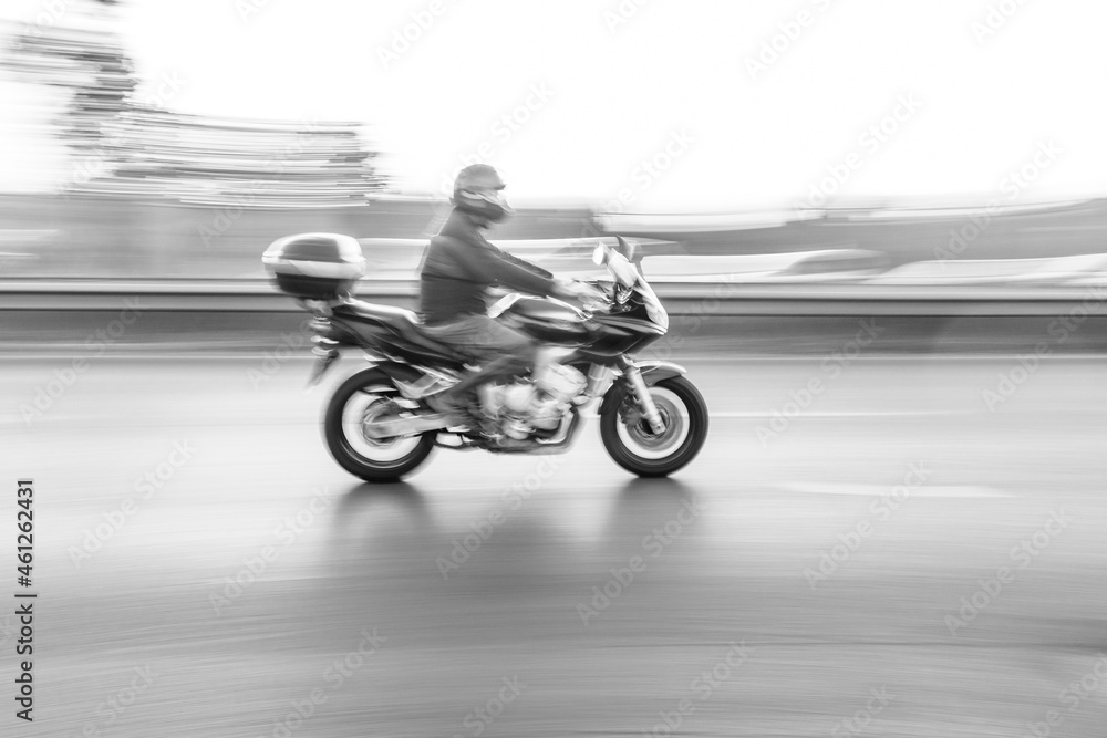 Fototapeta premium a man riding a bike. Motorcycle speed motion blur on the road black and white