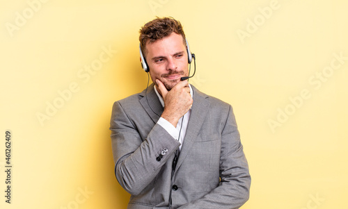 young handsome man smiling with a happy, confident expression with hand on chin. telemarketer concetp photo