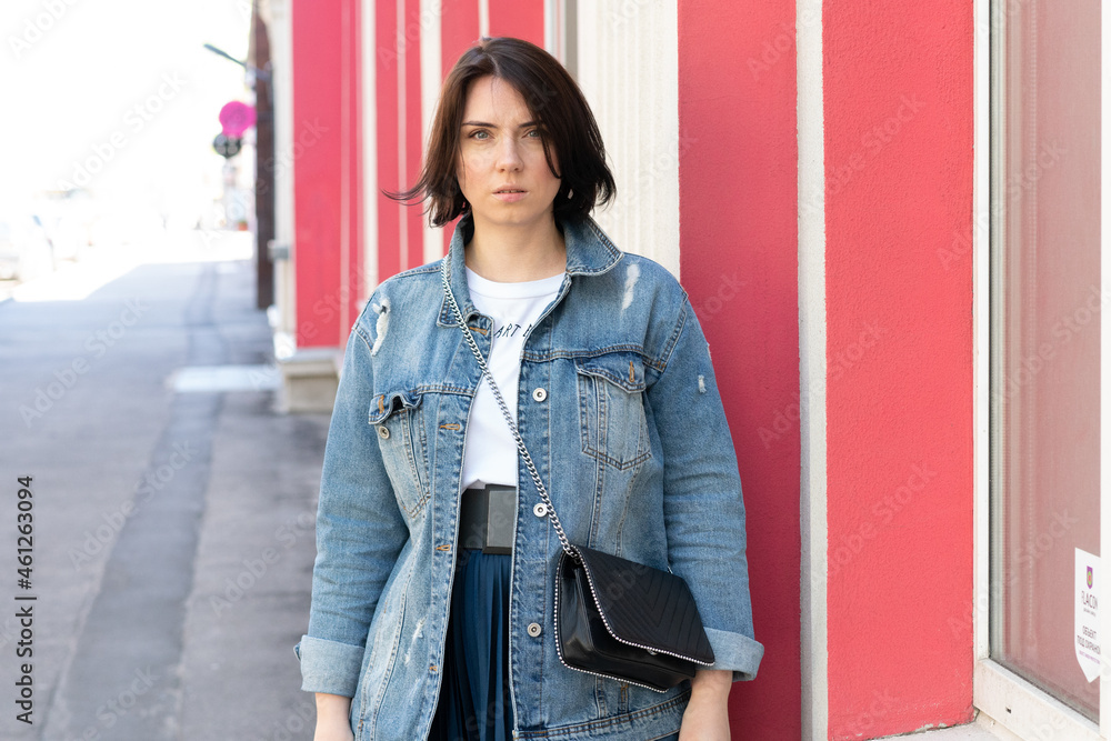 portrait of a young beautiful woman in the city, stands in a denim jacket portrait of a young beautiful woman in the city, stands in a denim jacket