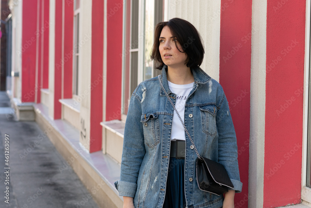 portrait of a young beautiful woman in the city, stands in a denim jacket portrait of a young beautiful woman in the city, stands in a denim jacket