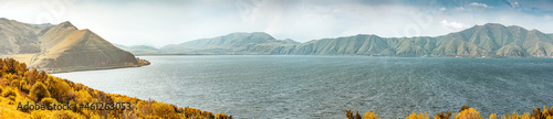 Panoramic view of famous Sevan lake with bald mountain ranges. Dramatic and harsh northern landscape. Tourist attractions in Armenia photo