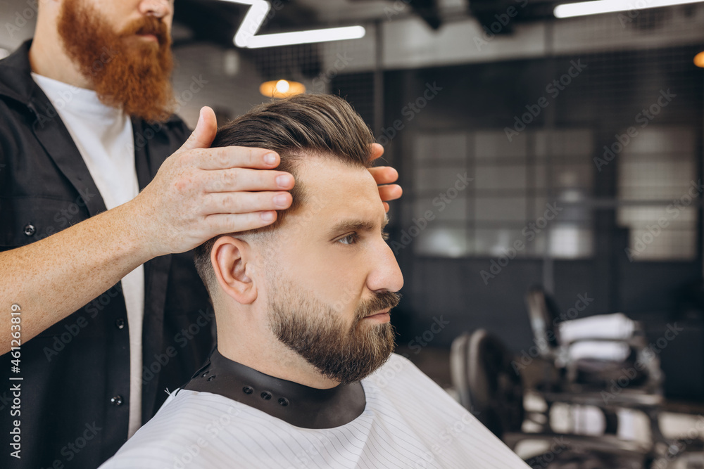 Stylish man getting haircut at the barbershop. Professional barber at work process. Beauty, selfcare, style, fashion and male cosmetics concept. Stylish man getting haircut at the barbershop. Professional barber at work process. Beauty, selfcare, style, fashion and male cosmetics concept.