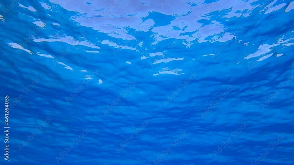 Blue water surface with small waves. Natural background with sun glints on surface of blue water. Texture of blue water surface of sea reflection of sun's rays. Underwater shot, 4K-60fps Blue water surface with small waves. Natural background with sun glints on surface of blue water. Texture of blue water surface of sea reflection of sun's rays. Underwater shot, 4K-60fps