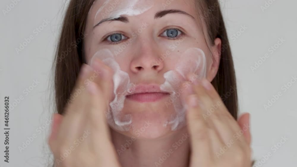 Young woman applying cleansing foam to her face close-up. Young woman applying cleansing foam to her face close-up.