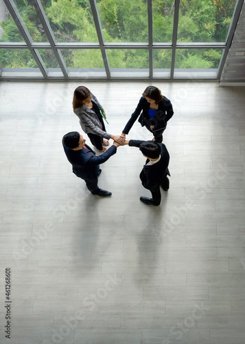 Business partners join hands in the modern office. Standing near the window in the hallway