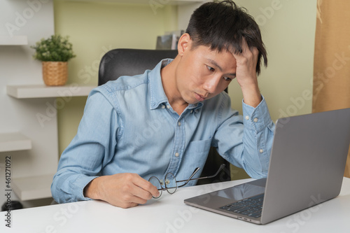 stressed young Asian man touch head after lose money from trading, investing on stock trading or cryptocurrency platform. Investing on stock or Cryptocurrency is high risk. Young money concept.