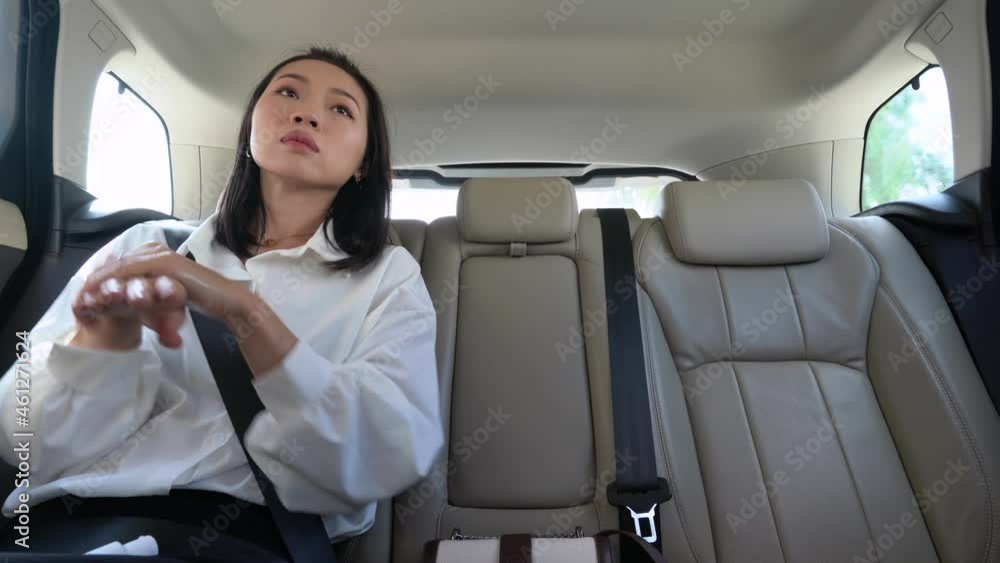 Asian woman applying sanitizer on hands on backseat in taxi Asian woman applying sanitizer on hands on backseat in taxi