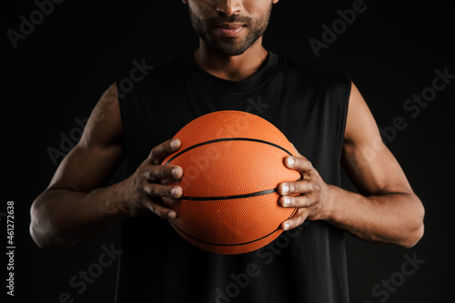 Young sportsman looking at camera while posing with basketball © Drobot Dean