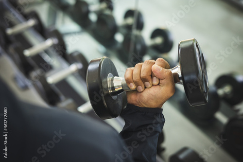 Young Fitness man with dumbbell in gym. Guy weight training wearing sportswear. Asian man exercise indoor gym lifting dumbbell. Bodybuilder good health