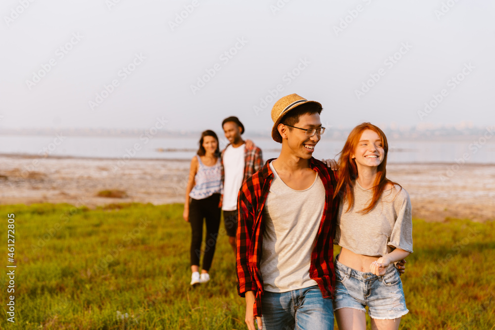 Multiracial two couples hugging and smiling while hiking outdoors Multiracial two couples hugging and smiling while hiking outdoors