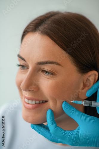 Cosmetologist injecting collagen to her clients face