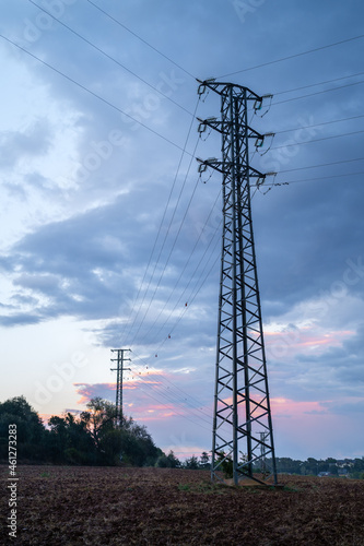 high voltage tower in wheat field  at sunset with blue and purple clouds, Catalonia, Spain