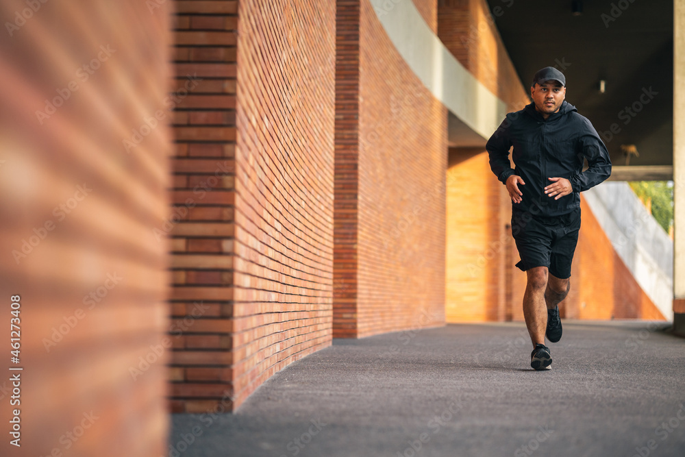 Asia man wearing jacket sportswear running on the road under the building. Young man jogging for exercise in the city. healthy lifestyle and sports concept Asia man wearing jacket sportswear running on the road under the building. Young man jogging for exercise in the city. healthy lifestyle and sports concept