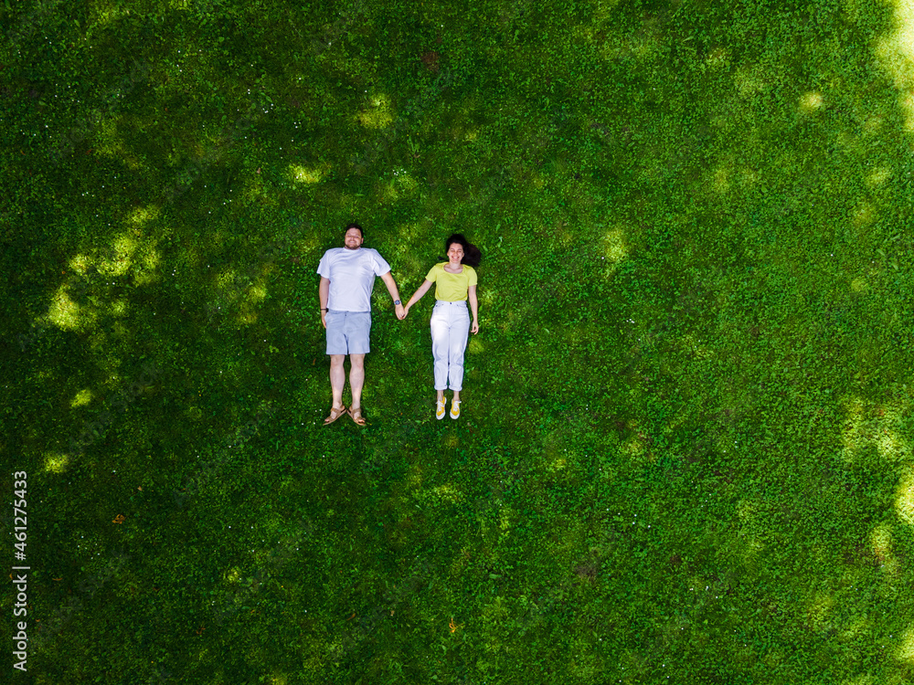 smiling couple laying down on green grass smiling couple laying down on green grass