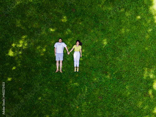 smiling couple laying down on green grass © phpetrunina14