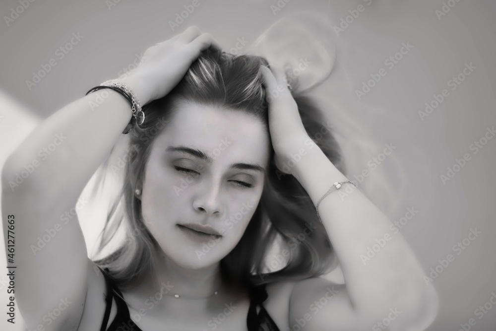 Naklejka premium Beautiful blonde girl with closed eyes holding her hair with her hands