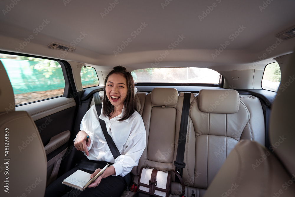 Laughing ethnic woman taking notes in notebook in taxi Laughing ethnic woman taking notes in notebook in taxi
