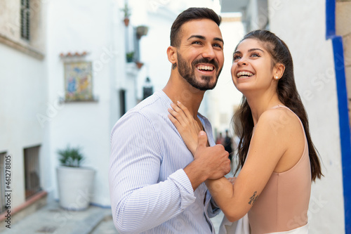 Cheerful Hispanic couple embracing in city
