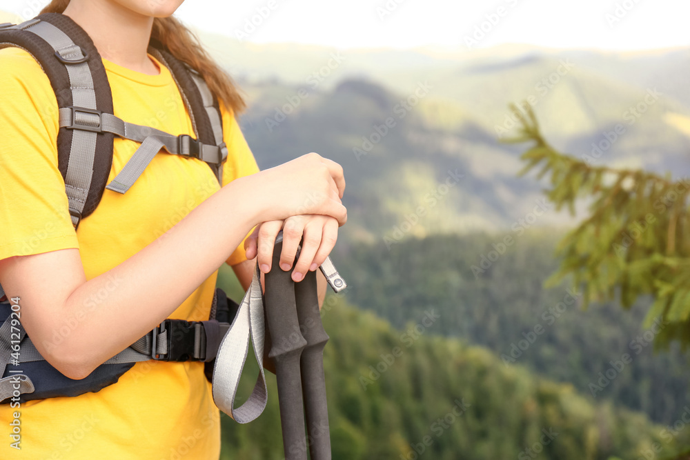 Woman with backpack and trekking poles hiking in mountains, closeup. Space for text