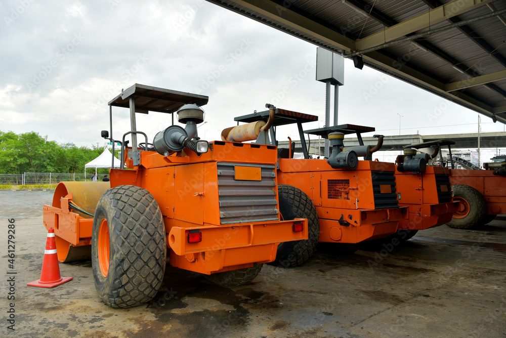 An orange road roller is parked in the company.