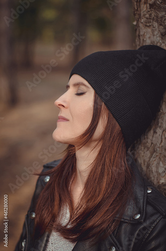 Portrait of a beautiful young woman in a hat near a tree, close-up