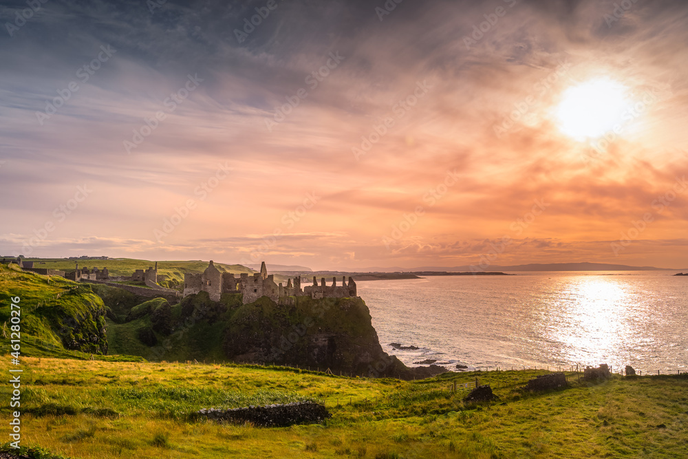 Dramatic sunset at medieval ruins of Dunluce Castle, perched on the cliff, Bushmills, Northern Ireland. Filming location of popular TV show Game of Thrones