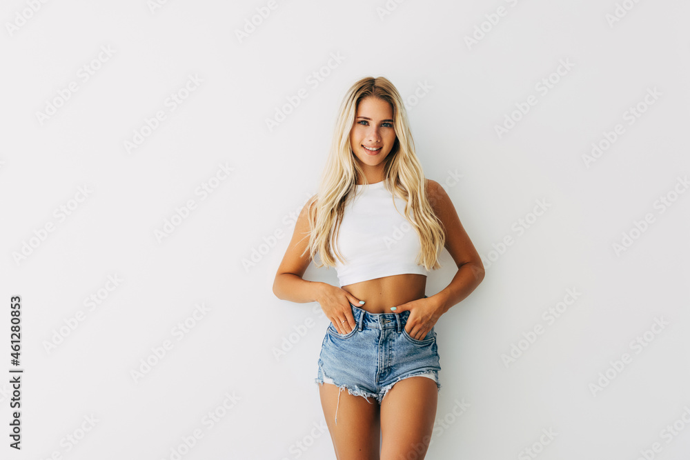 Charming friendly blonde smiling woman in white t-shirt and blue jeans looking at camera isolated on white background