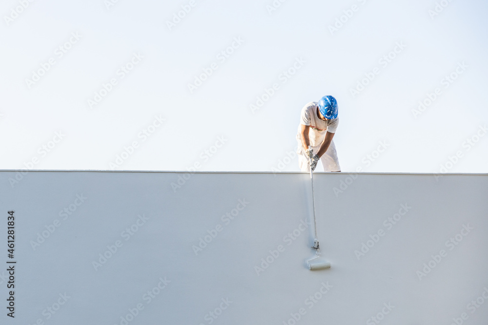 © ADDICTIVE STOCK - Front view of a young painter painting from the roof