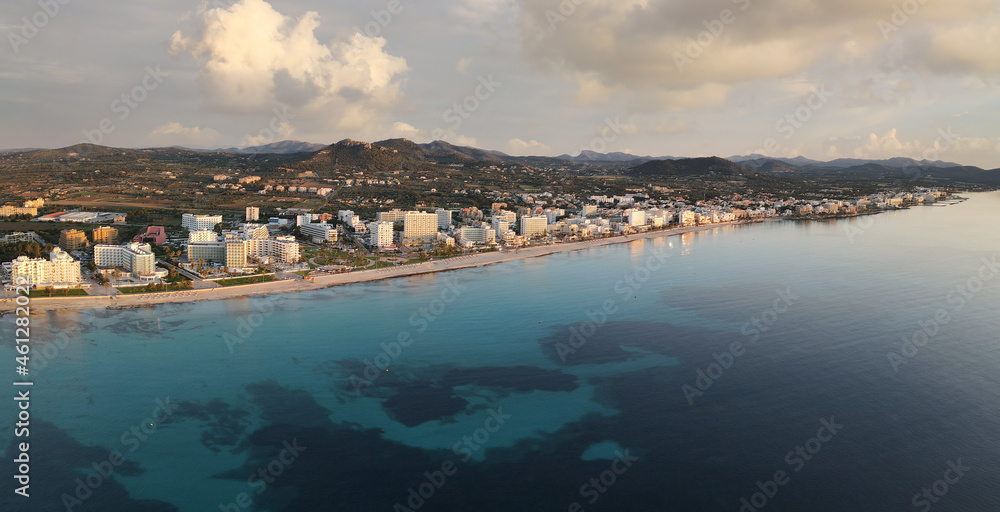 Aerial view of the town of Cala Millor on the east coast of the Spanish Mediterranean island of Mallorca. It's after sunrise. Below you can see the long beach and beautiful clouds in the sky.