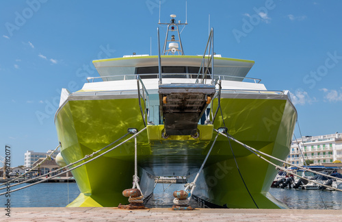 The small port of Cala Bona on the east coast of the Mediterranean island of Mallorca. A catamaran has moored at the quay wall. It is a summer day with sunshine. Other boats are in the harbor.