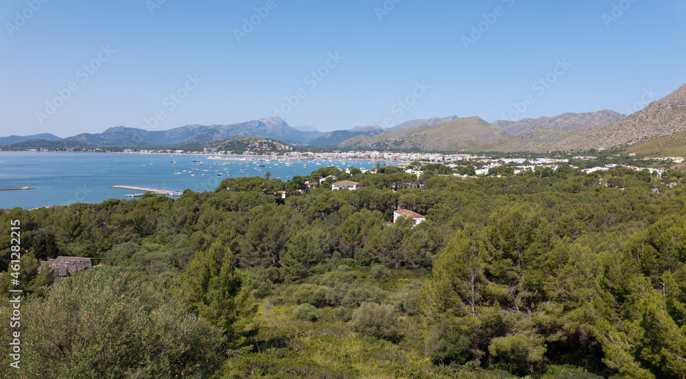 The bay of Pollenca on the Mediterranean island of Mallorca from the east. Many boats are moored in the bay. In the background are the highest mountains on the island.