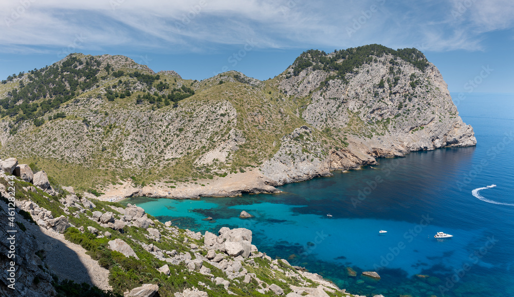 A dreamlike bay on the north side of the Formentor peninsula in the east of the Mediterranean island of Mallorca to the sea. Boats are anchored at the bottom right and one is just driving away.