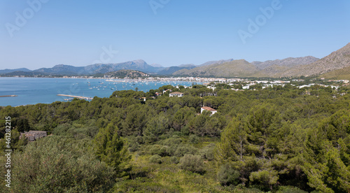 The bay of Pollenca on the Mediterranean island of Mallorca from the east. Many boats are moored in the bay. In the background are the highest mountains on the island.